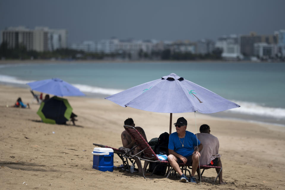 People relax on the shores of the Isla Verde public beach near a vaccination campaign as part of the “Noche de San Juan” festivities, a traditional all-day celebration to mark the birth of St. John the Baptist, in Carolina, Puerto Rico, Wednesday, June 23, 2021. This year COVID-19 vaccines will be available to devotees heading to the beach to celebrate the saint’s June 24th feast day. (AP Photo/Carlos Giusti)