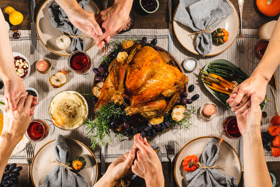 A top-down shot of a family Thanksgiving dinner with a turkey and various sides. (Photo via Getty Images)