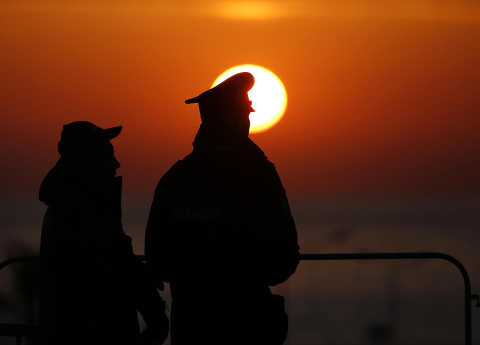 Olympic security personnel watch the sun set after the men's gold medal ice hockey game at the 2014 Winter Olympics, Sunday, Feb. 23, 2014, in Sochi, Russia. The game was the final competition of the winter games. (AP Photo/Petr David Josek)
