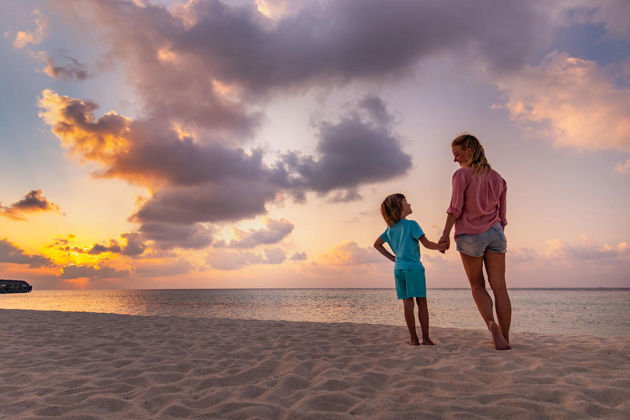 Happy mother and son holding hands and communicating while taking a walk on the beach Getty Images/skynesher