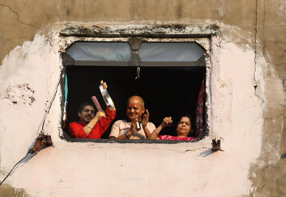 A family bang pans and claps from the window of their house in show of appreciation to health care workers in Prayagraj, India, Sunday, March 22, 2020. India is observing a 14-hour "people's curfew" called by Prime Minister Narendra Modi in order to stem the rising coronavirus caseload in the country of 1.3 billion. For most people, the new coronavirus causes only mild or moderate symptoms. For some it can cause more severe illness (AP Photo/Rajesh Kumar Singh)