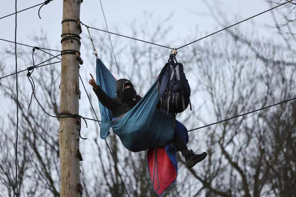 An ctivist gestures at the village Luetzerath near Erkelenz, Germany, Friday, Jan. 13, 2023. Police have entered the condemned village in to evict the climate activists holed up at the site in an effort to prevent its demolition, to make way for the expansion of a coal mine. (Rolf Vennenbernd/dpa via AP)