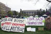 Signs are displayed outside a tent encampment at Northwestern University on Friday, April 26, 2024, in Evanston, Illinois. Students want the university to divest from funds connected to Israel or that profit from its war in Gaza. (AP Photo/Teresa Crawford)