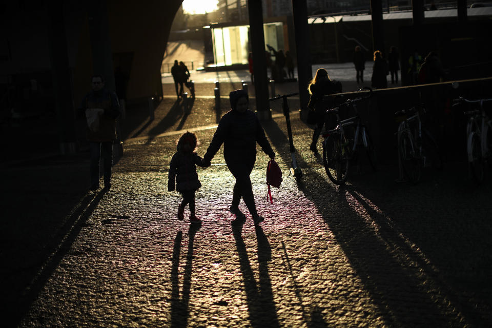 Commuters walk outside the EU headquarters in Brussels, Wednesday, Feb. 19, 2020. (AP Photo/Francisco Seco)