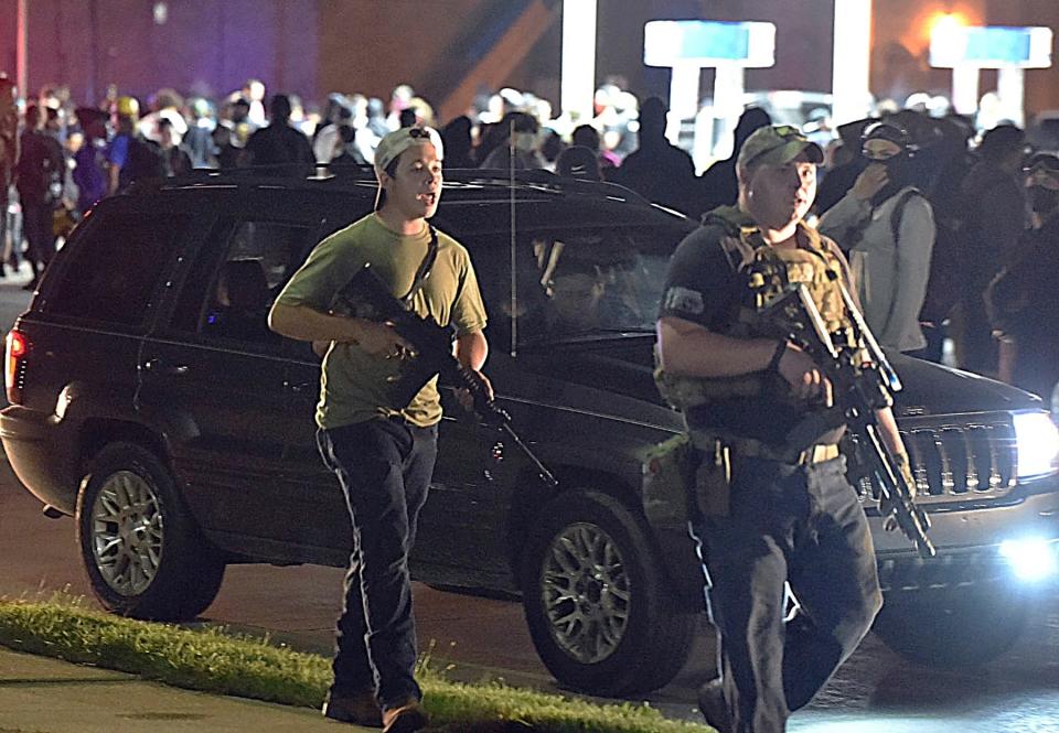 In this Aug. 25, 2020, file photo, Kyle Rittenhouse, left, with backward cap, walks along Sheridan Road in Kenosha, Wis., with another armed civilian. Rittenhouse was among a number of armed men who converged on the city this summer, claiming to protect property owners from arson and theft.