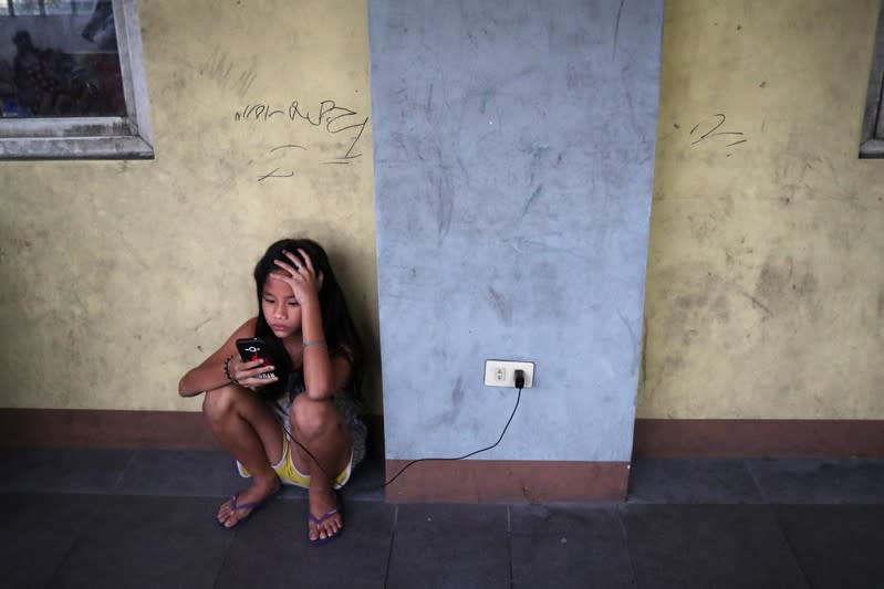 A girl charges her phone at the Delpan Evacuation Center after Typhoon Kammuri hit Metro Manila