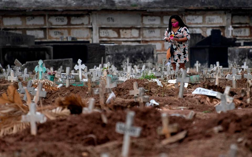 A woman visits a relative's grave at a cemetery in Rio de Janeiro, Brazil - MAURO PIMENTEL/AFP 