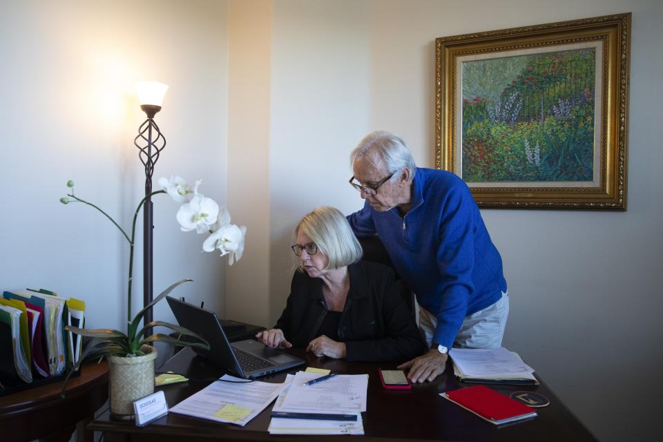 In this Feb. 6, 2019, photo Debbie Douglas works on her computer as her husband and business partner, Gary, watches in their home office in Newport Beach, Calif. In business together for 16 years, the Douglases have found that being co-owners of a public relations firm requires them to be more direct with each other than they once were as spouses. (AP Photo/Jae C. Hong)