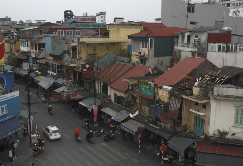 In this Feb. 14, 2014 photo, cars and motorcycles pass in Hanoi's Old Quarter, a grouping of 36 streets that were laid out in the 15th century. Tourists, hawkers and motorcyclists rub shoulders here every morning. It seems generations away from the office towers and electronics megastores springing up in other parts of the capital. (AP Photo/Mike Ives)