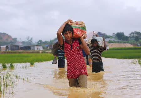 Rohingya refugees carry their belongings as they walk through a flooded pathway at a camp in Cox's Bazar, Bangladesh September 19, 2017. REUTERS/Danish Siddiqui
