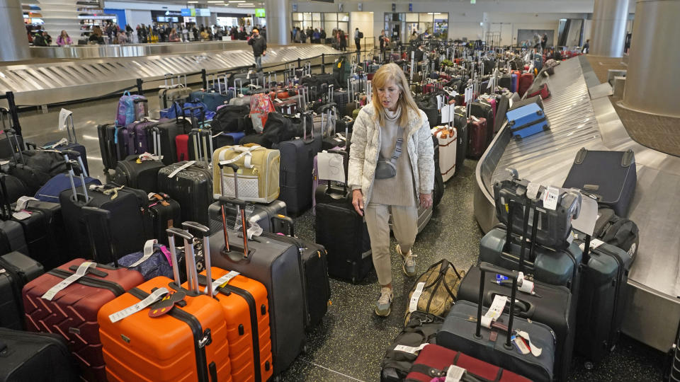 Chicago traveler Shana Schifer walks through unclaimed bags at Southwest Airlines baggage claim at Salt Lake City International Airport Thursday, Dec. 29, 2022, in Salt Lake City. Southwest Airlines said it expects to return to normal operations Friday after slashing about two-thirds of its schedule in recent days, including canceling another 2,350 flights Thursday. (AP Photo/Rick Bowmer)