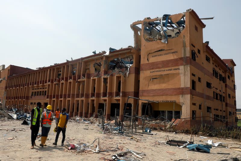 Rescue workers walk past the building of a school that was affected by a pipeline explosion at Abule Ado in Lagos