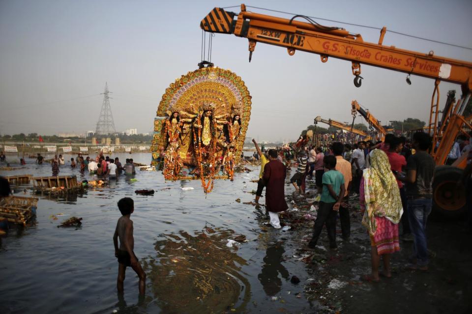 FILE- In this Tuesday, Oct. 11, 2016 file photo, a giant Idol of Hindu goddess Durga suspends from a crane before it is immersed in the River Yamuna during Durga Puja festival in New Delhi, India. A court in northern India has granted the same legal rights as a human to the Ganges and Yamuna rivers, considered sacred by nearly a billion Indians. The Uttaranchal High Court in Uttarakhand state ruled Monday, March 20, 2017, that the two rivers be accorded the status of living human entities, meaning that if anyone harms or pollutes the rivers, the law would view it as no different from harming a person. (AP Photo/Altaf Qadri, File)