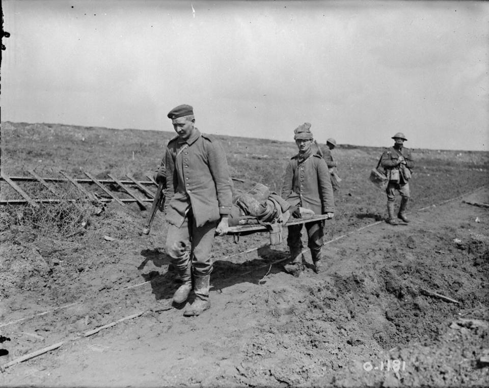 Two men carry a wounded soldier.