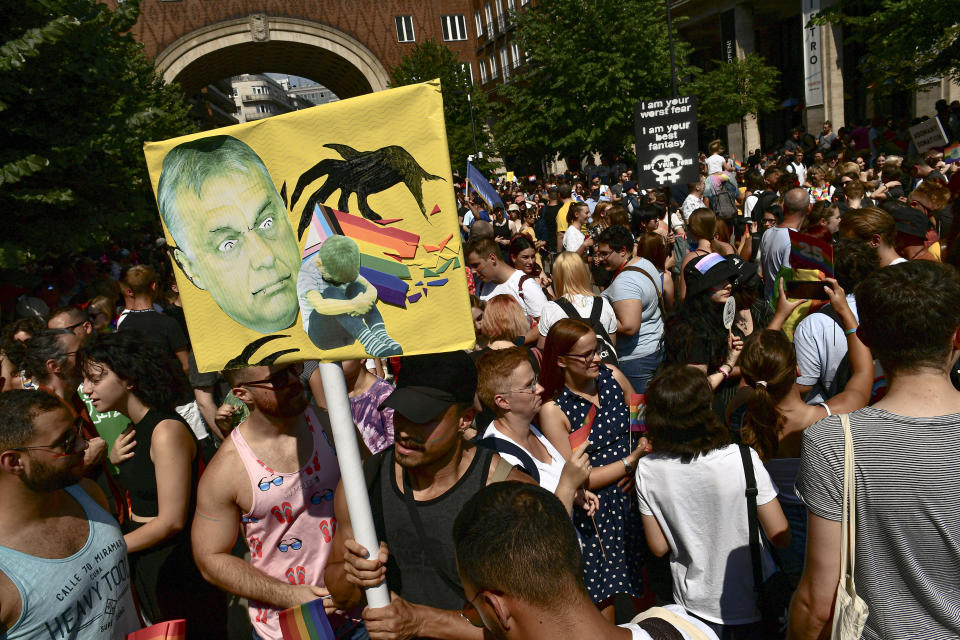 People taking part in a gay pride parade hold a banner depicting Hungarian Prime Minister Viktor Orban in Budapest, Hungary, Saturday, July 24, 2021. Hungary's government led by right-wing Prime Minister Viktor Orban passed a law in June prohibiting the display of content depicting homosexuality or gender reassignment to minors, a move that has ignited intense opposition in Hungary while EU lawmakers have urged the European Commission to take swift action against Hungary unless it changes tack. (AP Photo/Anna Szilagyi)