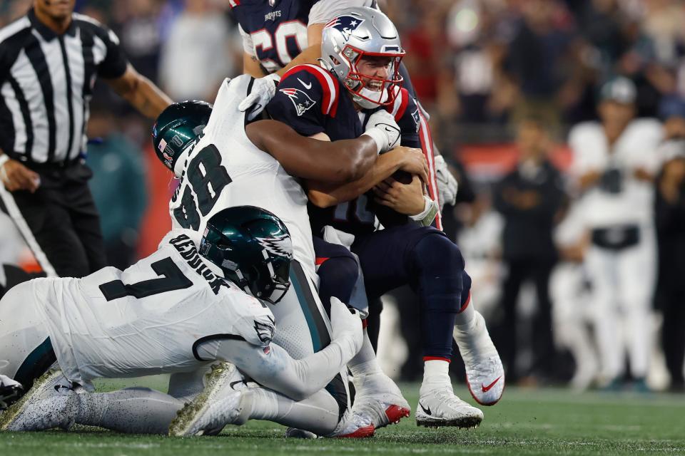 New England Patriots quarterback Mac Jones, top right, is brought down by Philadelphia Eagles linebacker Haason Reddick (7) and defensive tackle Jalen Carter, center left, in the second half of an NFL football game, Sunday, Sept. 10, 2023, in Foxborough, Mass.