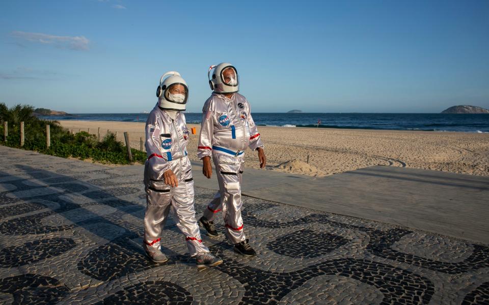 Accountant Tercio Galdino and wife Alicea walk in astronaut costumes as a way to protect themselves from COVID-19 and draw awareness to protective measures along Ipanema beach  - Bruna Prado/AP