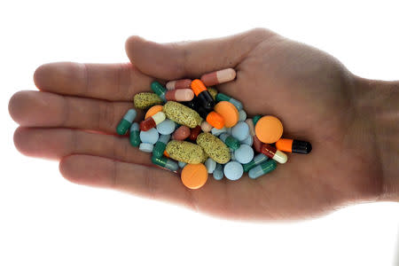 FILE PHOTO: A person holds pharmaceutical tablets and capsules in this picture illustration taken in Ljubljana September 18, 2013. REUTERS/Srdjan Zivulovic