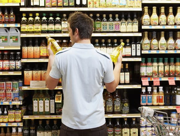 Young man comparing products in a supermarket.