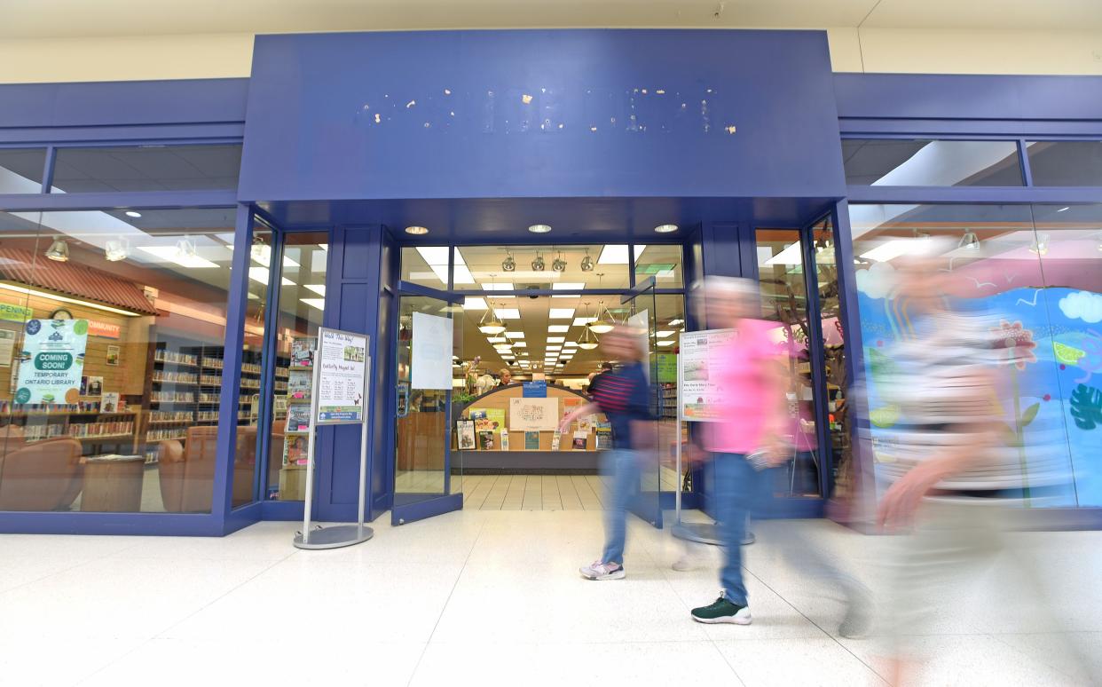 Mall walkers speed by the new location of the Ontario Branch of the Mansfield/Richland County Library on Monday morning.