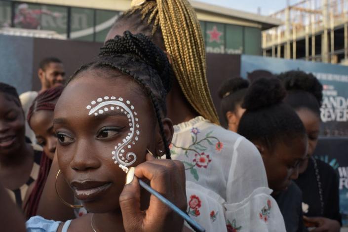 A woman gets her face painted before the premiere of &quot;Black Panther: Wakanda Forever&quot; in Lagos, on November 6, 2022. - The African premiere of the Marvel superhero film &quot;Black Panther: Wakanda Forever&quot; is taking place in Lagos, a leading commercial hub for African entertainment ahead of the film's global release on November 11.