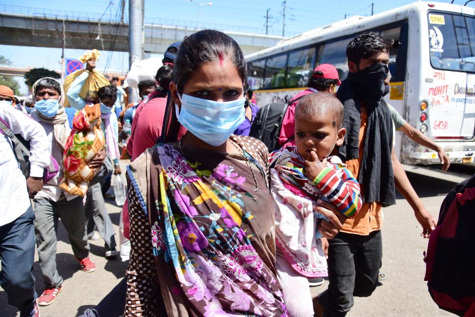 DELHI, INDIA - 2020/03/29: Migrant woman with a baby wearing a face mask as a preventive measure, at Anand vihar bus terminal during the nationwide lock down. The Indian government imposed a 21 day nationwide lock down as a preventive measure against the corona virus pandemic. (Photo by Manish rajput/SOPA Images/LightRocket via Getty Images)