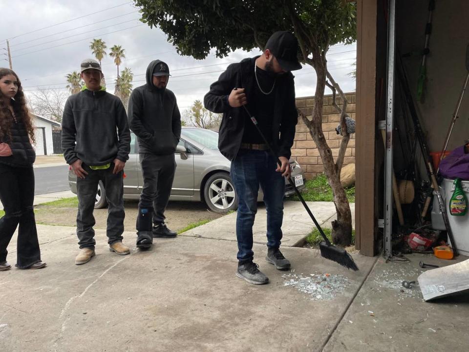 Relatives sweep broken glass following a crash that hospitalized a 10-year-old girl on Saturday afternoon, Feb. 25, 2023.