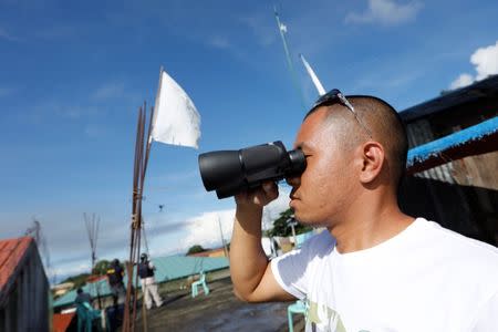 Men watch from a rooftop during the Philippines army airstrike as government troops continue their assault against insurgents from the Maute group in Marawi city June 27, 2017. REUTERS/Jorge Silva