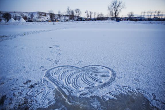 A heart decorates the snow on the icy Cannonball River at the Oceti Sakowin camp after it was announced that the U.S. Army Corps of Engineers won't grant easement for the Dakota Access oil pipeline in Cannon Ball, N.D., Sunday, Dec. 4, 2016. (AP Photo/David Goldman)