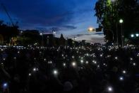 Protesters hold their mobiles with lanterns on during a protest demanding the resignation of the government in Bangkok