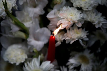 A candle and flowers, offered by people to pay tribute to the victims of the attack on the Holey Artisan Bakery and the O'Kitchen Restaurant, are pictured at a makeshift memorial near the site of the attack, in Dhaka, Bangladesh, July 3, 2016. REUTERS/Adnan Abidi