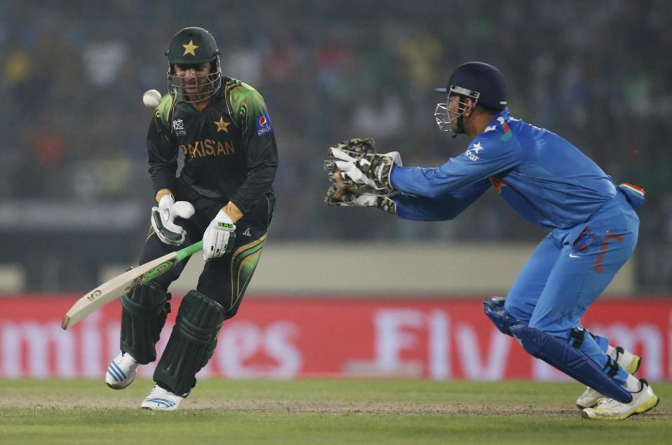 Pakistan's batsman Shoaib Malik, left, attempts to play the ball as India's captain Mahendra Singh Dhoni runs to catch it during their ICC Twenty20 Cricket World Cup match in Dhaka, Bangladesh, Friday, March 21, 2014. (AP Photo/Aijaz Rahi)