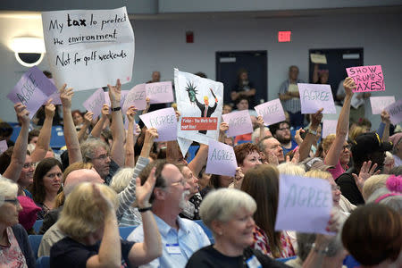 Attendees react with signs as U.S. Representative Ted Yoho (R-FL) answers a question posed to him about forcing President Trump to release his tax returns during a town hall meeting in Gainesville, Florida, U.S., April 10, 2017. REUTERS/Phelan Ebenhack