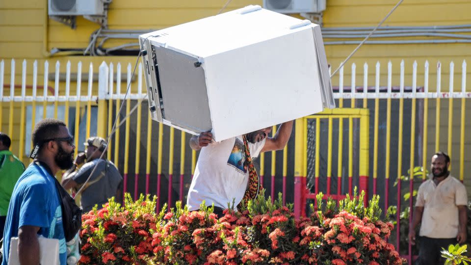 A man carries off a freezer as crowds disperse. - Andrew Kutan/AFP/Getty Images
