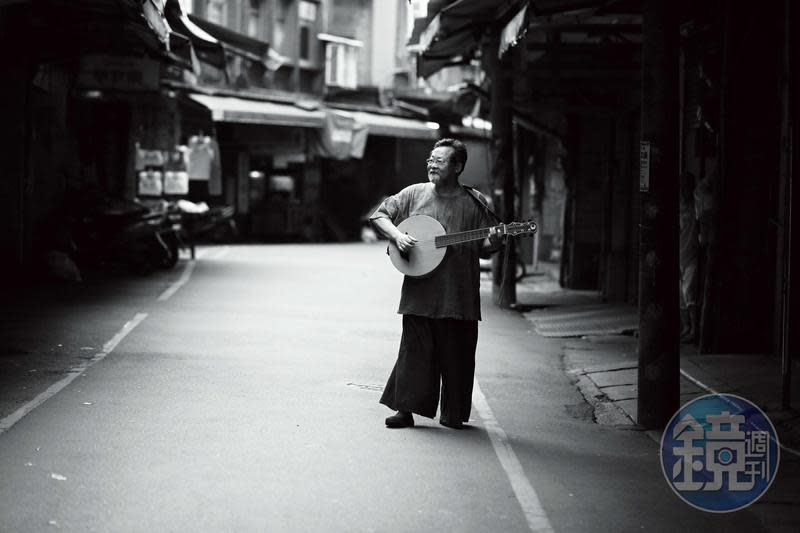 陳明章在北投市場巷弄內。拍攝照片時，他隨手一彈便是《戀戀風塵》配樂的即興演奏。