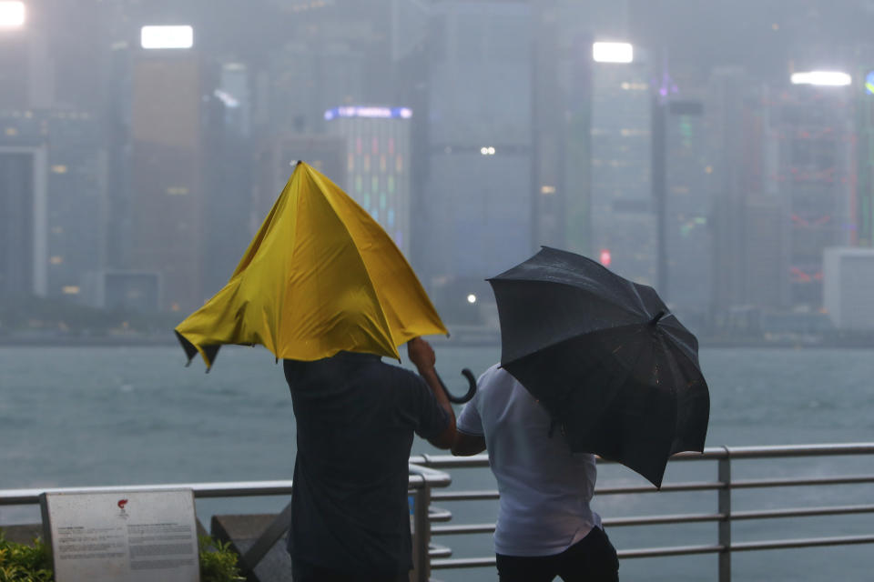 People with umbrellas struggle against the strong wind and rain brought by super typhoon Saola in Hong Kong, on Friday, Sept. 1, 2023. Most of Hong Kong and other parts of southern China ground to a near standstill Friday with classes and flights canceled as powerful Typhoon Saola approached. (AP Photo/Daniel Ceng)