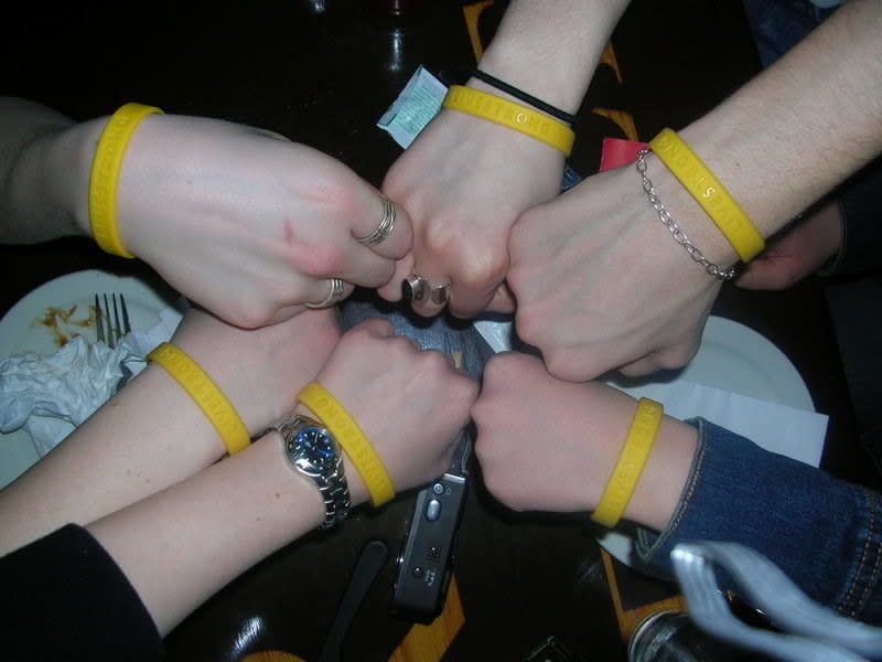 six people making a fist circle all wearing LiveStrong bracelets