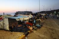 Migrants sleep outside their tents as they remained camped out on a road leading from Moria to the capital of Mytilene, on the northeastern island of Lesbos, Greece, Thursday, Sept. 17, 2020. Fires swept through the overcrowded camp at Moria on two nights last week, prompting more than 12,000 migrants and refugees to flee. Most of them remain without shelter even though emergency tents are available at another island site where a new camp is being built. (AP Photo/Petros Giannakouris)