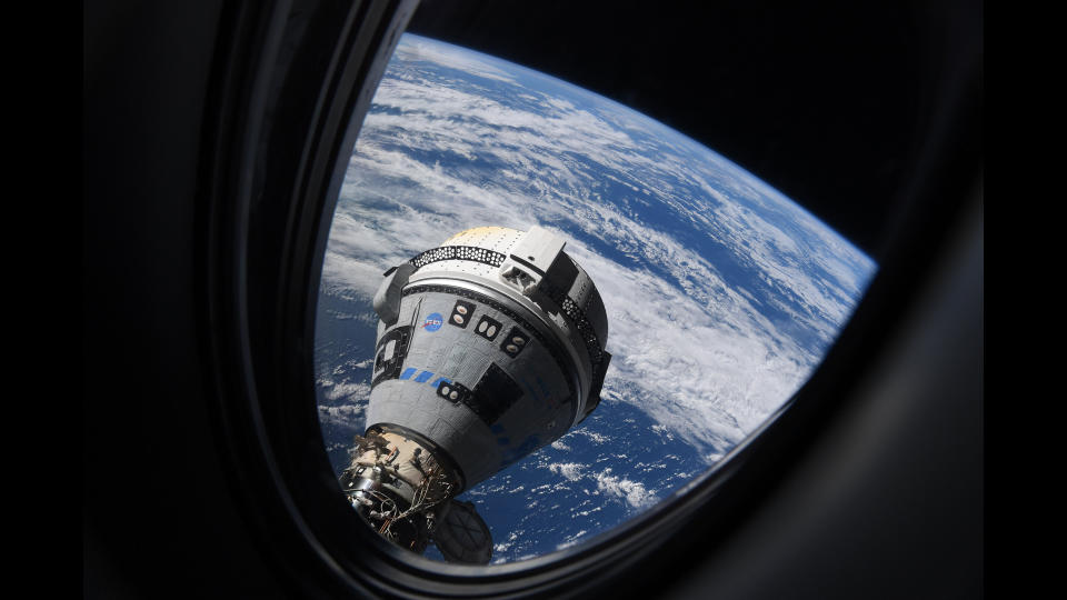a grey-and-blue cone-shaped spacecraft seen through a window with earth below