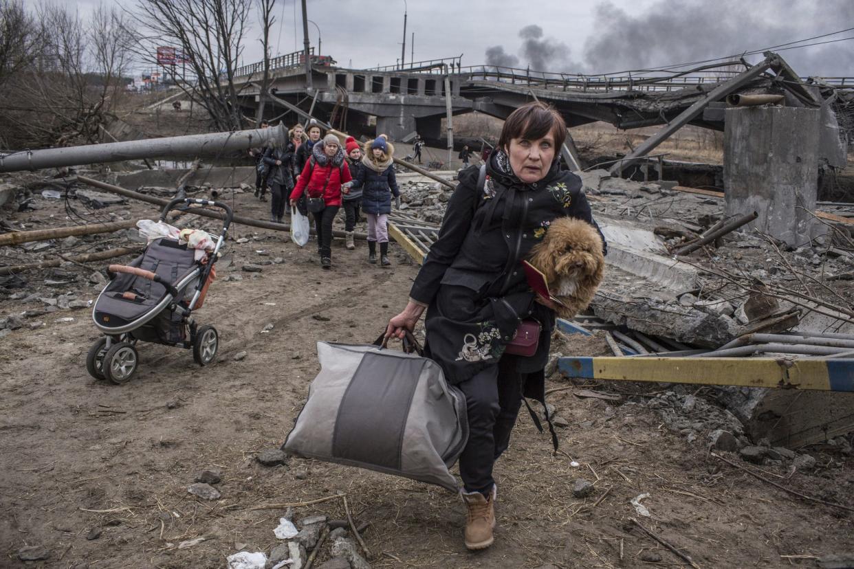 People cross an improvised path under a destroyed bridge while fleeing the town of Irpin, Ukraine on March 6, 2022. In Irpin, near Kyiv, a sea of people on foot and even in wheelbarrows trudged over the remains of a destroyed bridge to cross a river and leave the city.
