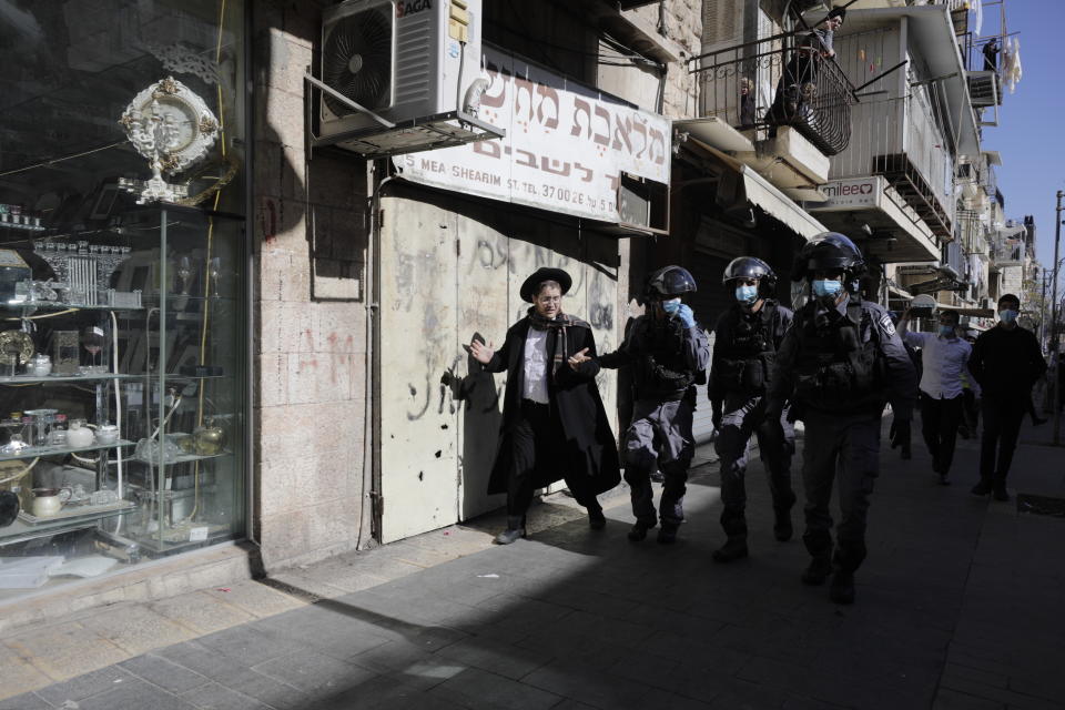 Israeli police officers detain an ultra-Orthodox man in Jerusalem, Sunday, Jan. 24, 2021. Ultra-Orthodox demonstrators clashed with Israeli police officers dispatched to close schools in Jerusalem and Ashdod that had opened in violation of health regulations on Sunday. (AP Photo/Sebastian Scheiner)