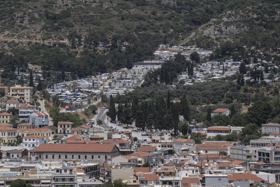 This shows the port city of Vathy and the refugee and migrant camp, top, in the eastern Aegean island of Samos, Greece, on Friday, June 11, 2021. An inflatable dinghy carrying nearly three dozen people reached the Greek island of Samos from the nearby Turkish coast. Within 24 hours, refugee rights groups say, the same group was seen drifting in a life raft back to Turkey. But of the 32 people determined to have initially made it to Samos, only 28 were in the raft the Turkish coast guard retrieved at sea. Days later, the missing four, a Palestinian woman and her three children, appeared in Samos' main town, apparently having eluded authorities. (AP Photo/Petros Giannakouris)