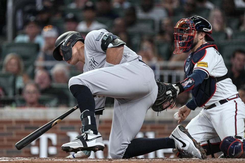 New York Yankees' Aaron Judge falls to a knee in front of Atlanta Braves catcher Travis d'Arnaud after a swinging strike during the sixth inning of a baseball game Wednesday, Aug. 16, 2023, in Atlanta. (AP Photo/John Bazemore)