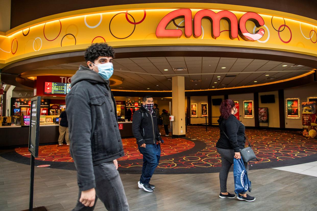 People wear face masks as they walk by a movie theater during the coronavirus disease (COVID-19) pandemic in Newport, New Jersey, U.S., April 2, 2021. REUTERS/Eduardo Munoz