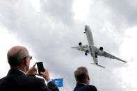 A visitor takes a picture of an Airbus A350-1000 as it performs during the 53rd International Paris Air Show at Le Bourget Airport near Paris