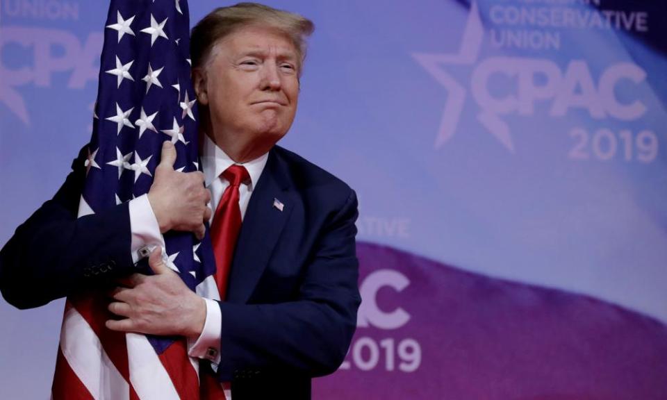 Donald Trump hugs an American flag at CPAC.