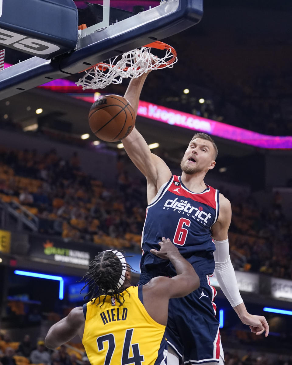 Washington Wizards' Kristaps Porzingis (6) dunks against Indiana Pacers' Buddy Hield (24) during the first half of an NBA basketball game Wednesday, Oct. 19, 2022, in Indianapolis. (AP Photo/Michael Conroy)