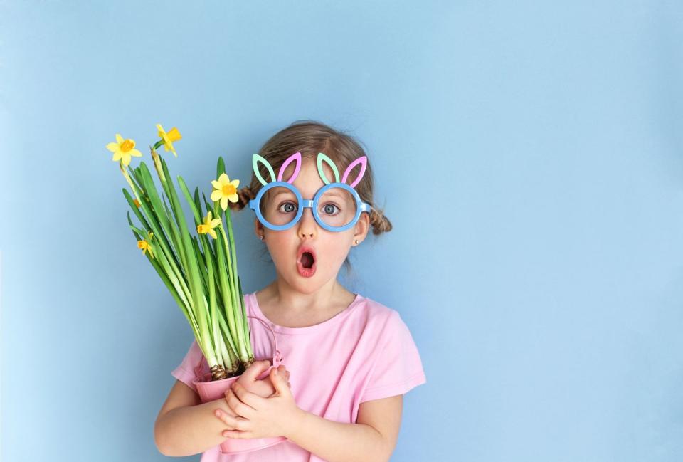 cute girl wearing bunny ears glasses and holding yellow daffodils