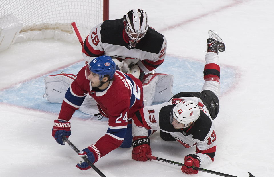 Montreal Canadiens' Phillip Danault (24) collides with New Jersey Devils goaltender Mackenzie Blackwood and Nico Hischier (13) during first-period NHL hockey game action in Montreal, Thursday, Nov. 28, 2019. (Graham Hughes/The Canadian Press via AP)