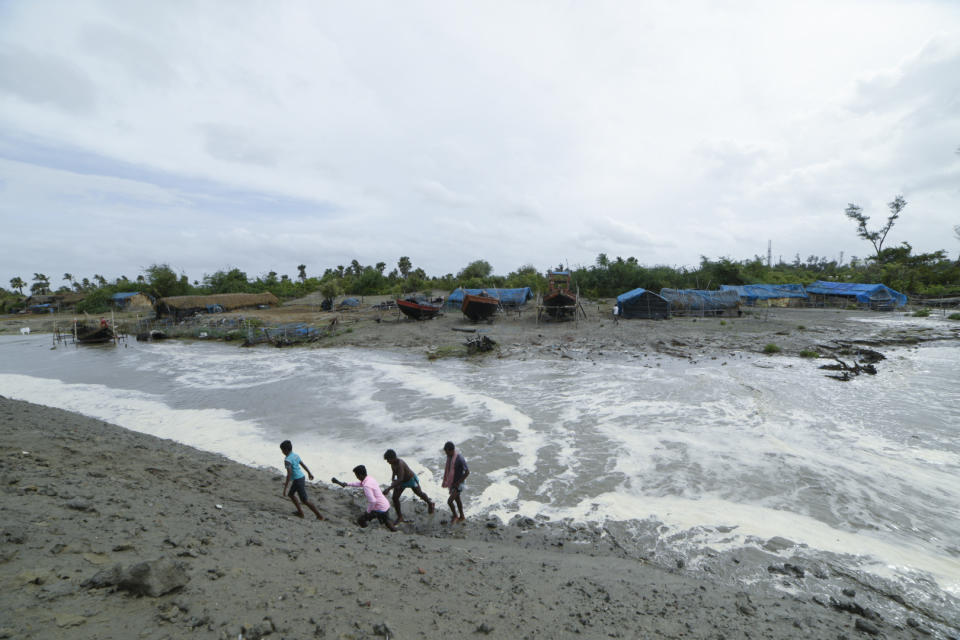 Village men walk past as sea water gushes in after breaking an embankment on the Bay of Bengal coast in South 24 parganas, West Bengal state, India, Tuesday, May 25, 2021. Tens of thousands of people are evacuating low-lying areas as Cyclone Yaas is expected to make landfall early Wednesday in Odisha and West Bengal states. (AP Photo/Mehaboob Uddin Gazi)